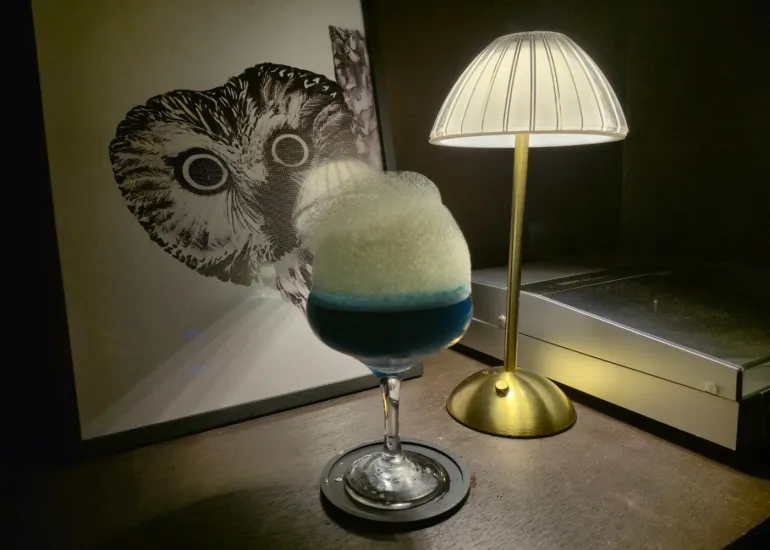 Blue Door signature cocktail, a striking blue drink with white foam topped in a goblet glass