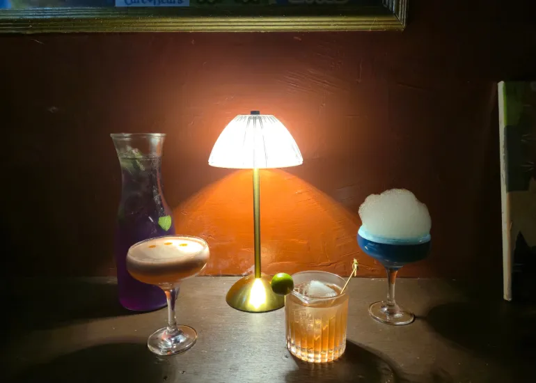 Intimate table setting with multiple craft cocktails lit by a warm lamp at Blue Door 304